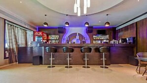 Eine Bar mit einer Theke, drei Barhocker und einem Coca-Cola-Kühlschrank.