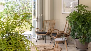 Un rincón interior acogedor con sillones de mimbre, una mesita y una planta grande en maceta.