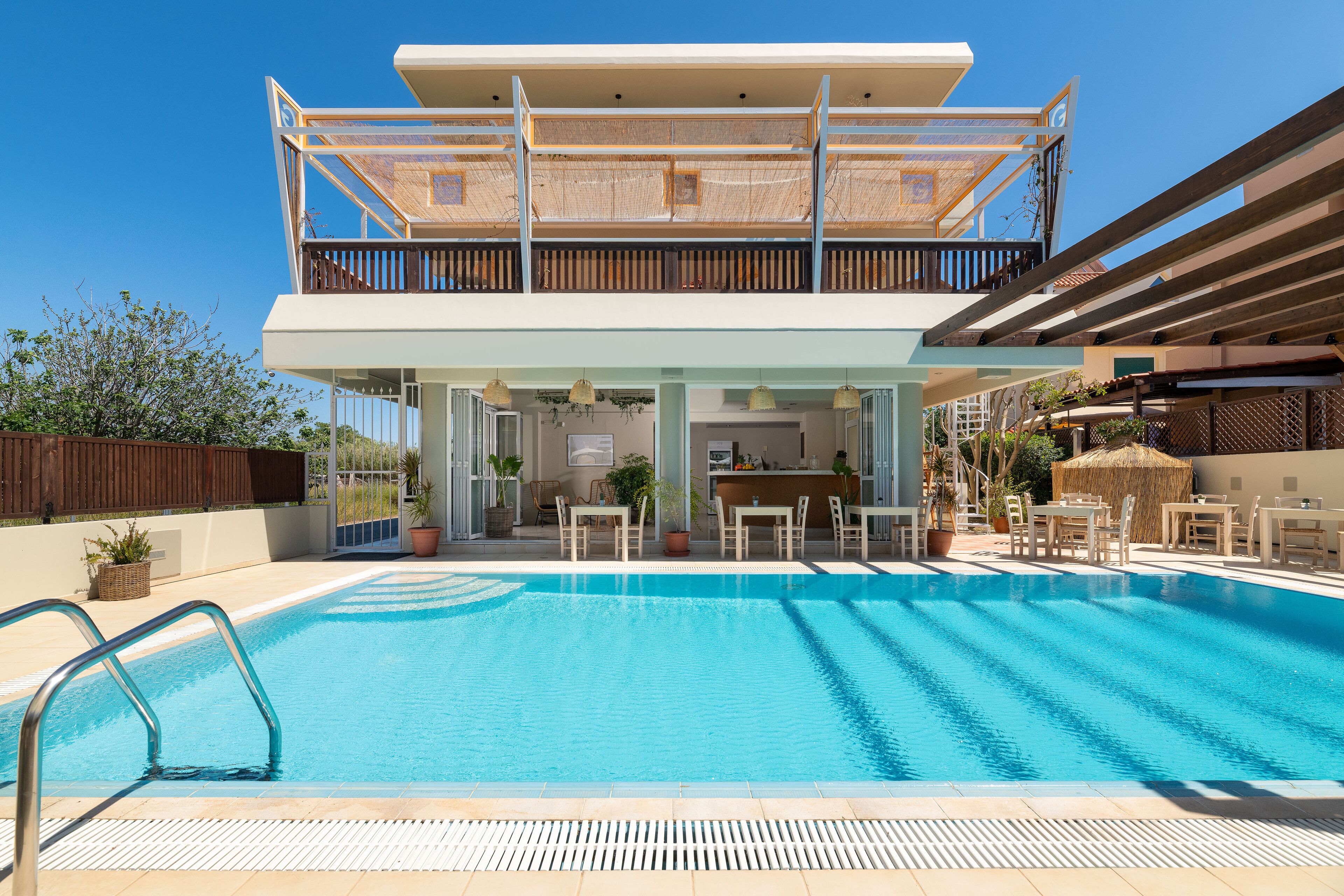 Un edificio moderno de dos pisos con piscina, asientos al aire libre y una zona de bar.