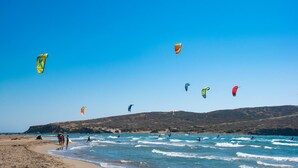 Una playa con cielos despejados y varios cometas de colores volando.