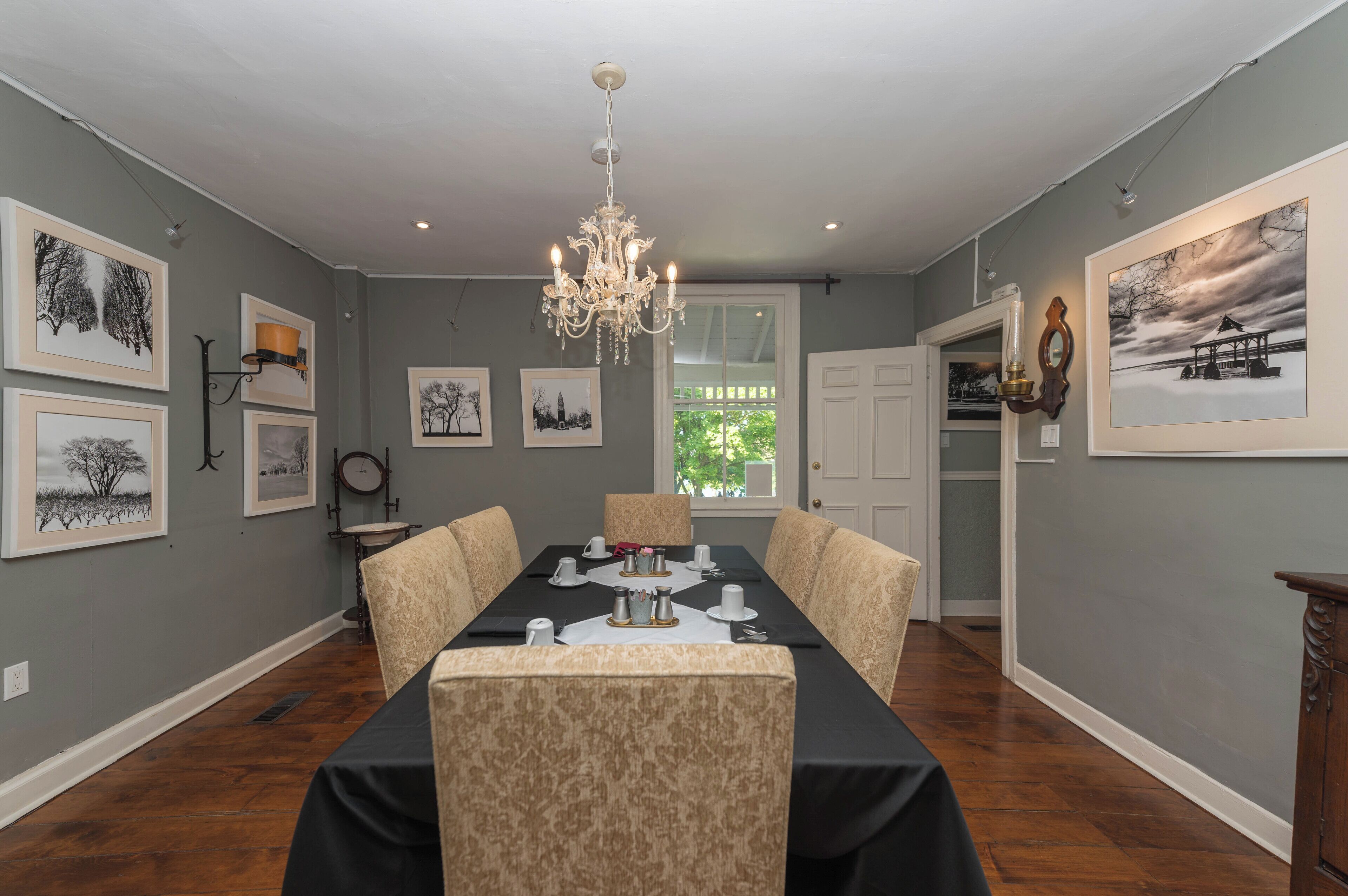 A dining room with a long table, chairs, and framed artwork on the walls.