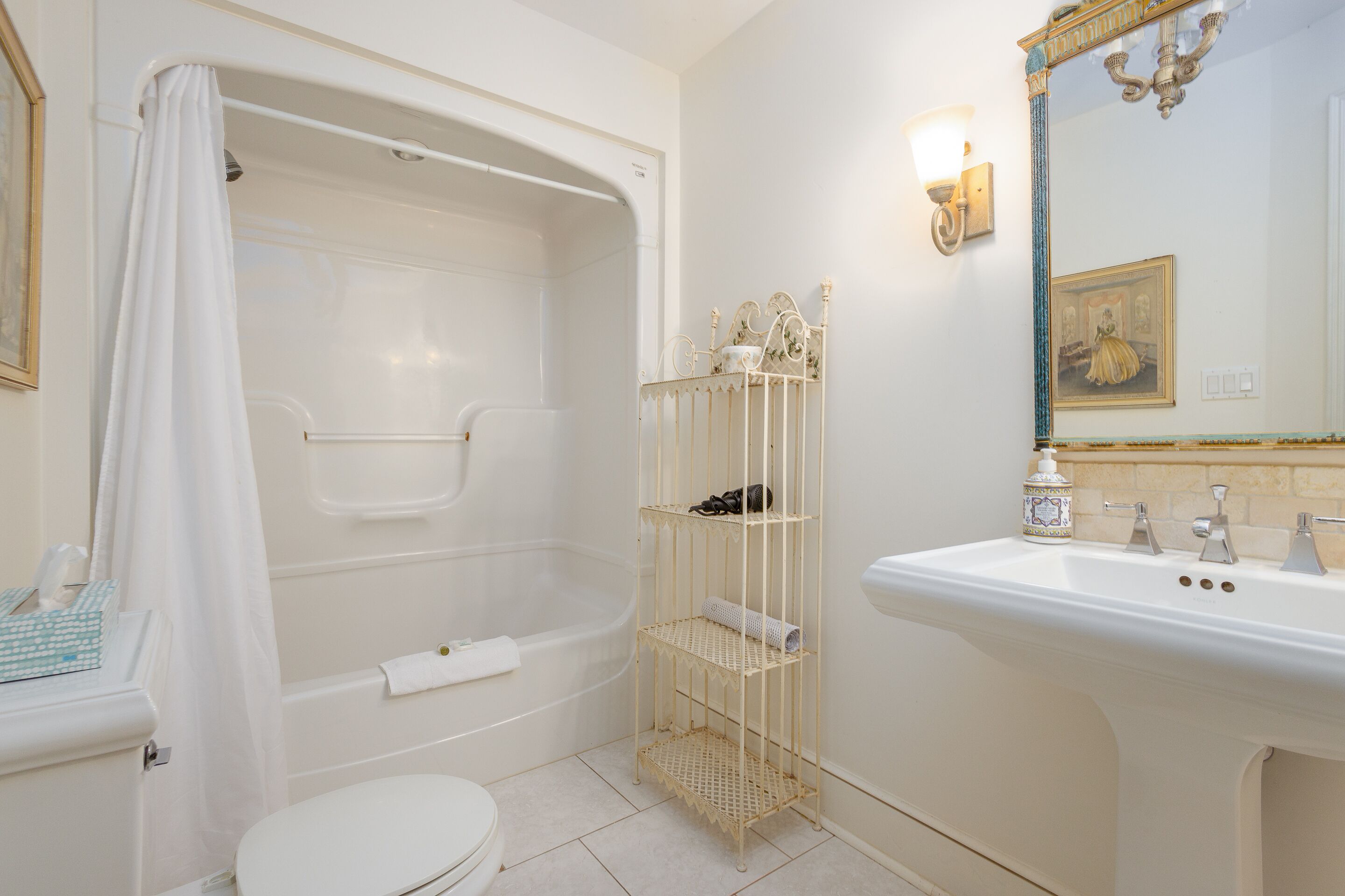 A bathroom with a bathtub, toilet, sink, and a shelf with toiletries.