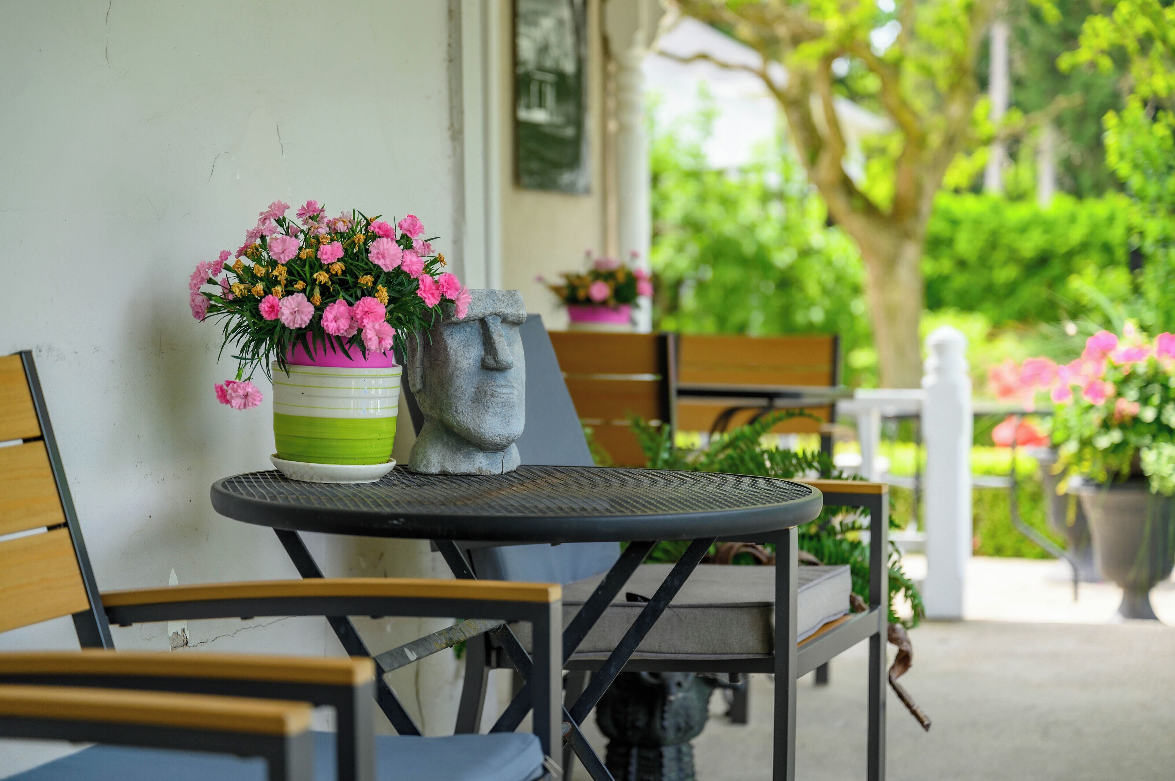 Un patio con una mesa redonda, sillas y plantas en macetas.