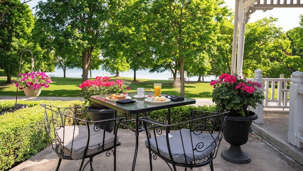 Un espace de restauration en plein air, avec une table et des chaises, entouré d’une végétation luxuriante et offrant une vue sur un plan d’eau.