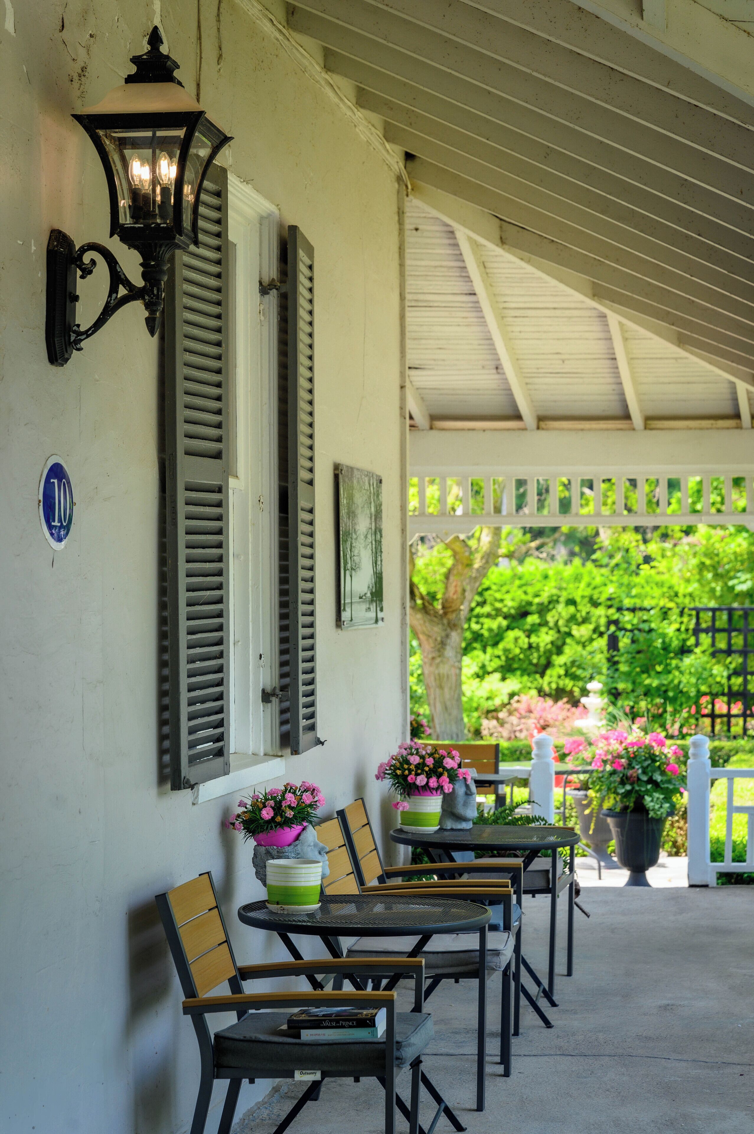 A covered porch with outdoor seating, a wall-mounted light fixture, and a number sign indicating the location.