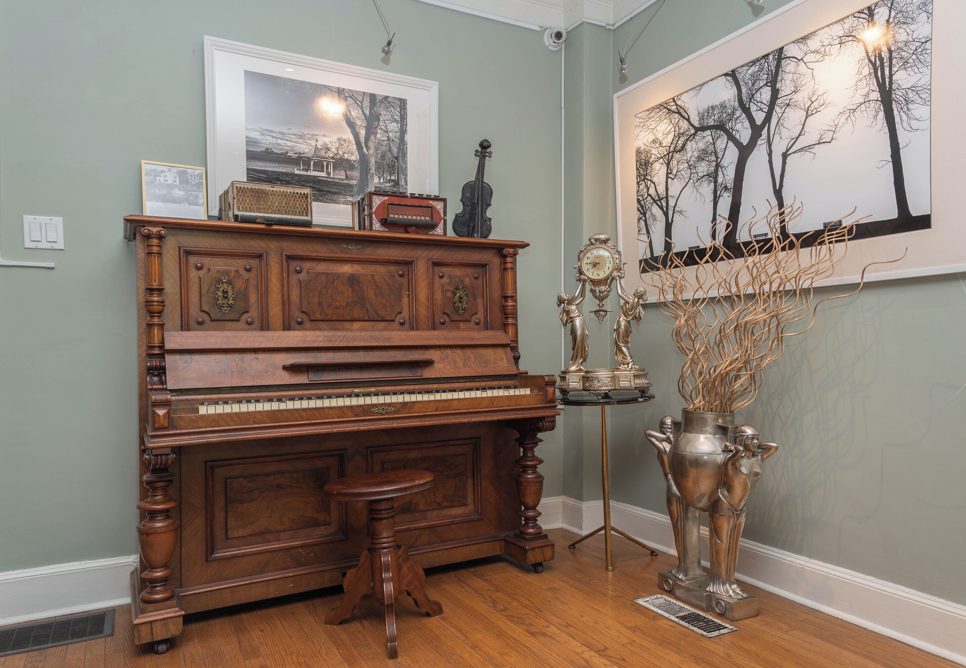 Um piano de cauda numa sala com um quadro emoldurado acima e uma pintura grande na parede.