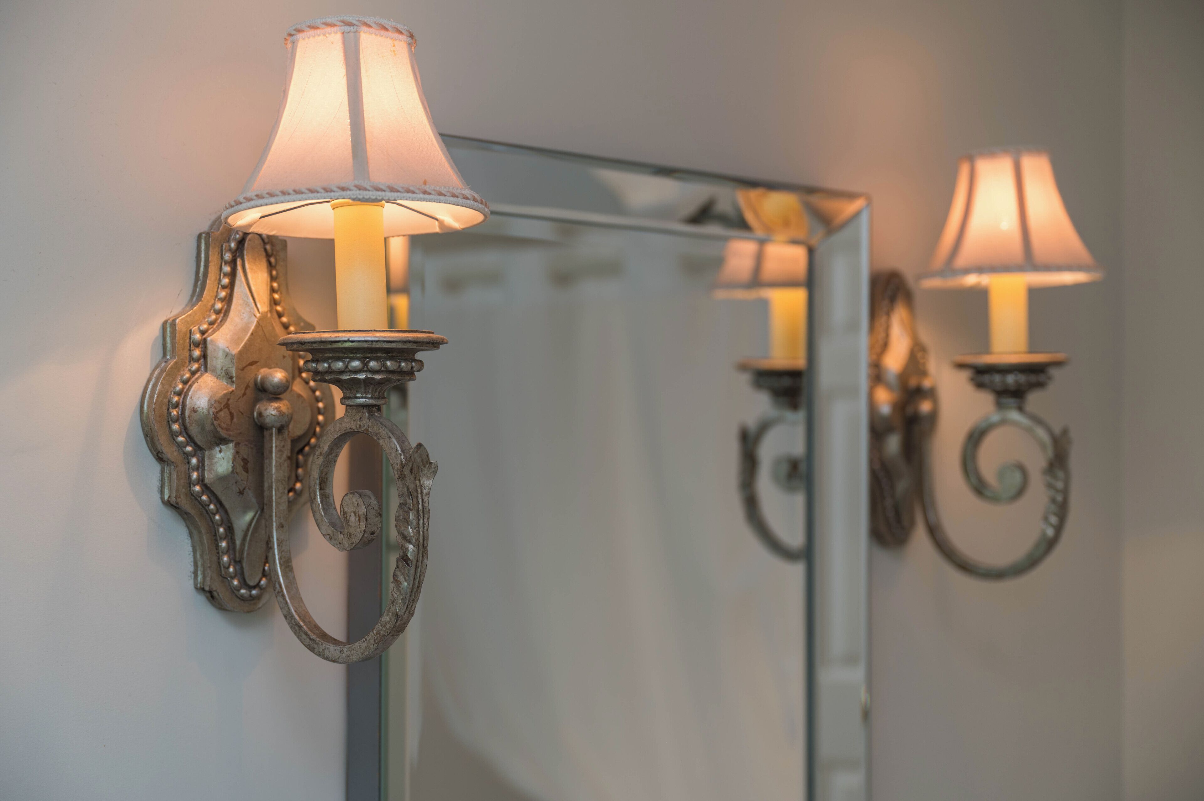 A wall-mounted lamp with a decorative metal frame and a lighted shade.