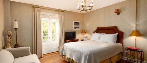 A hotel room with a large bed, a television, a desk, and a chair.