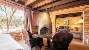A room with a fireplace, leather chairs, a sofa, and a bed.