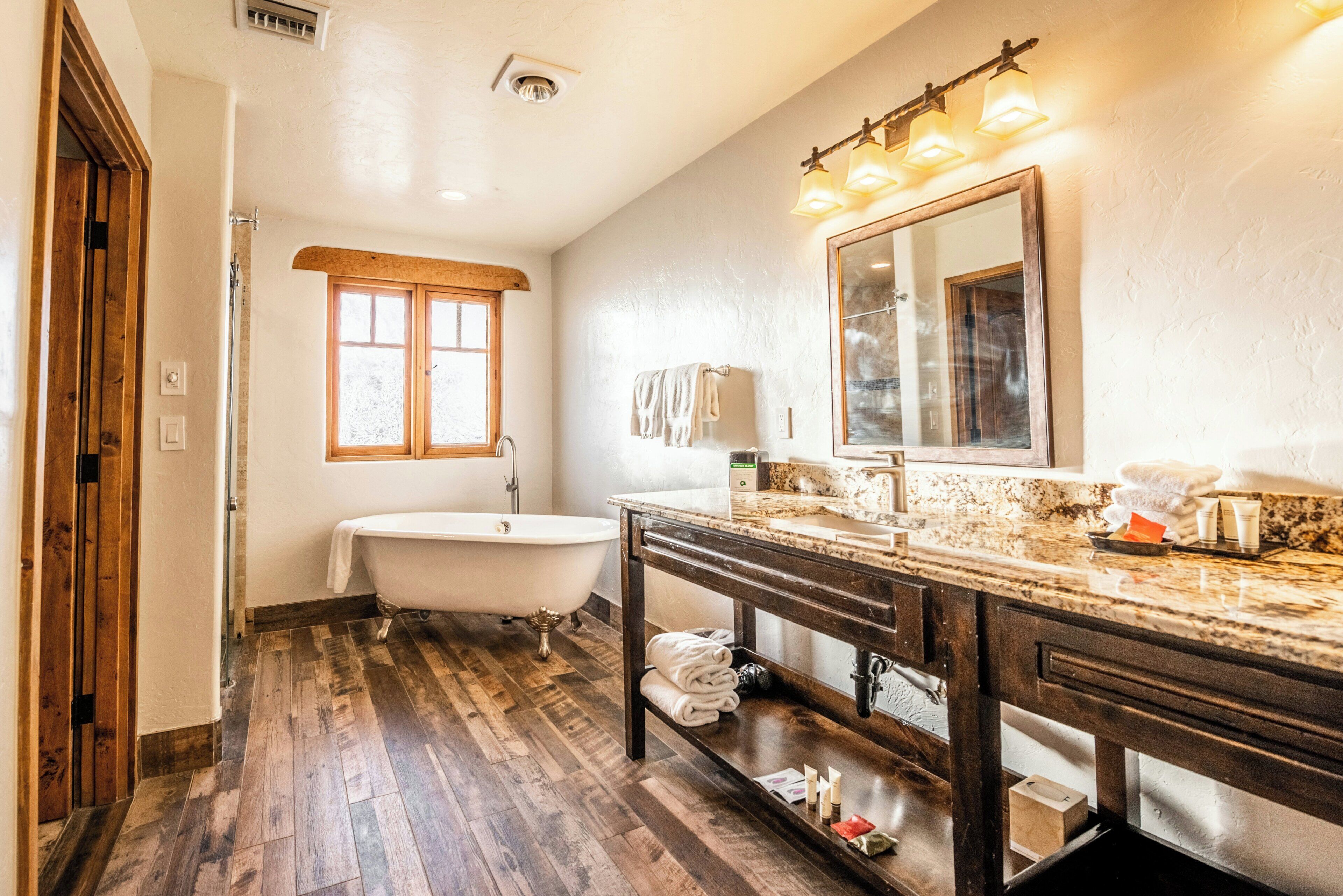 A bathroom with a bathtub, vanity, and a large mirror.