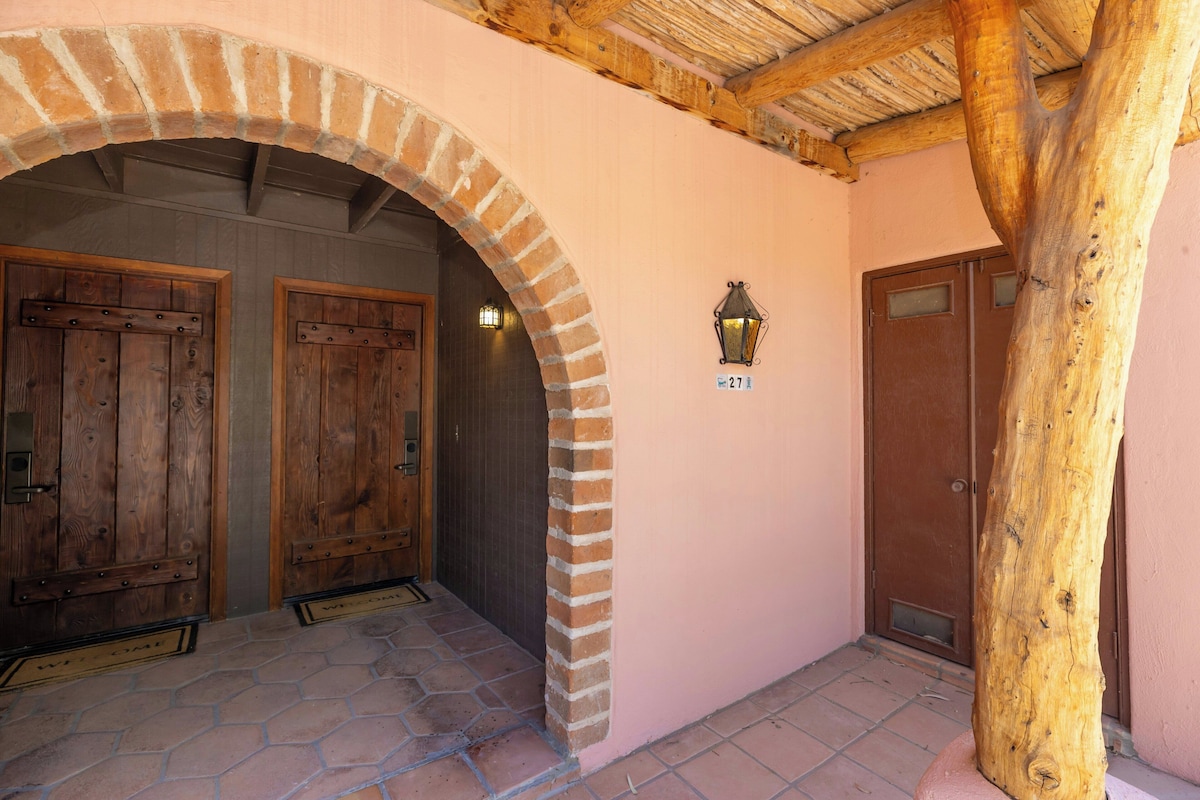 Una entrada de edificio con arco de ladrillo, puertas de madera, un farol y un poste de madera.