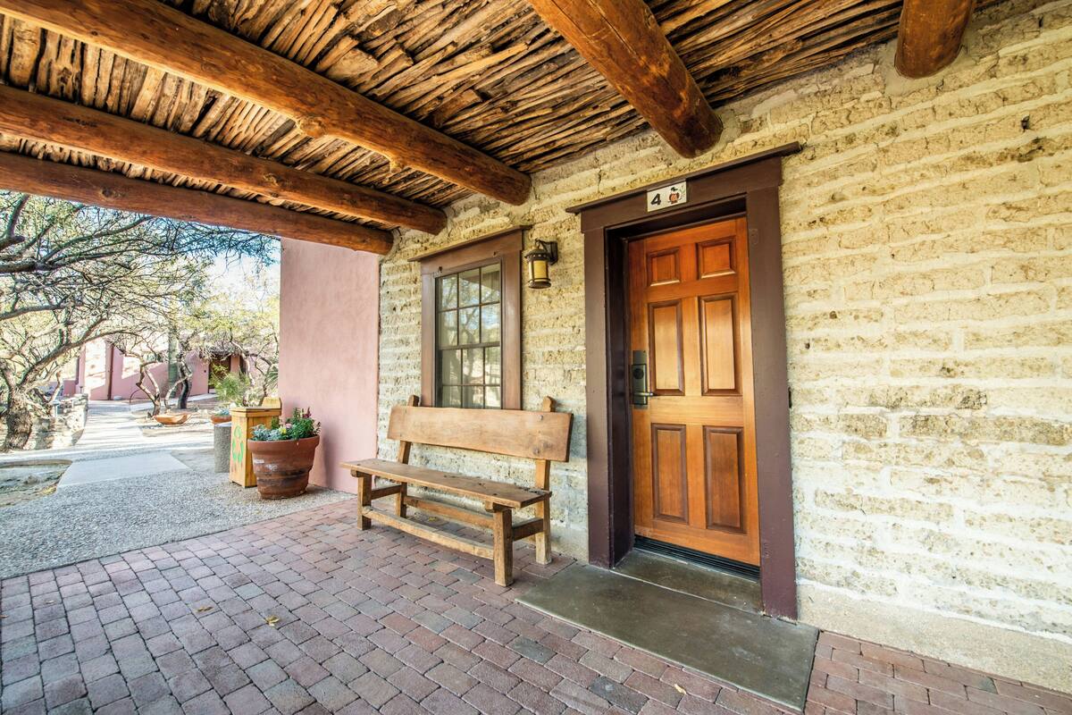 A stone building with a wooden door, a bench, and a lantern.