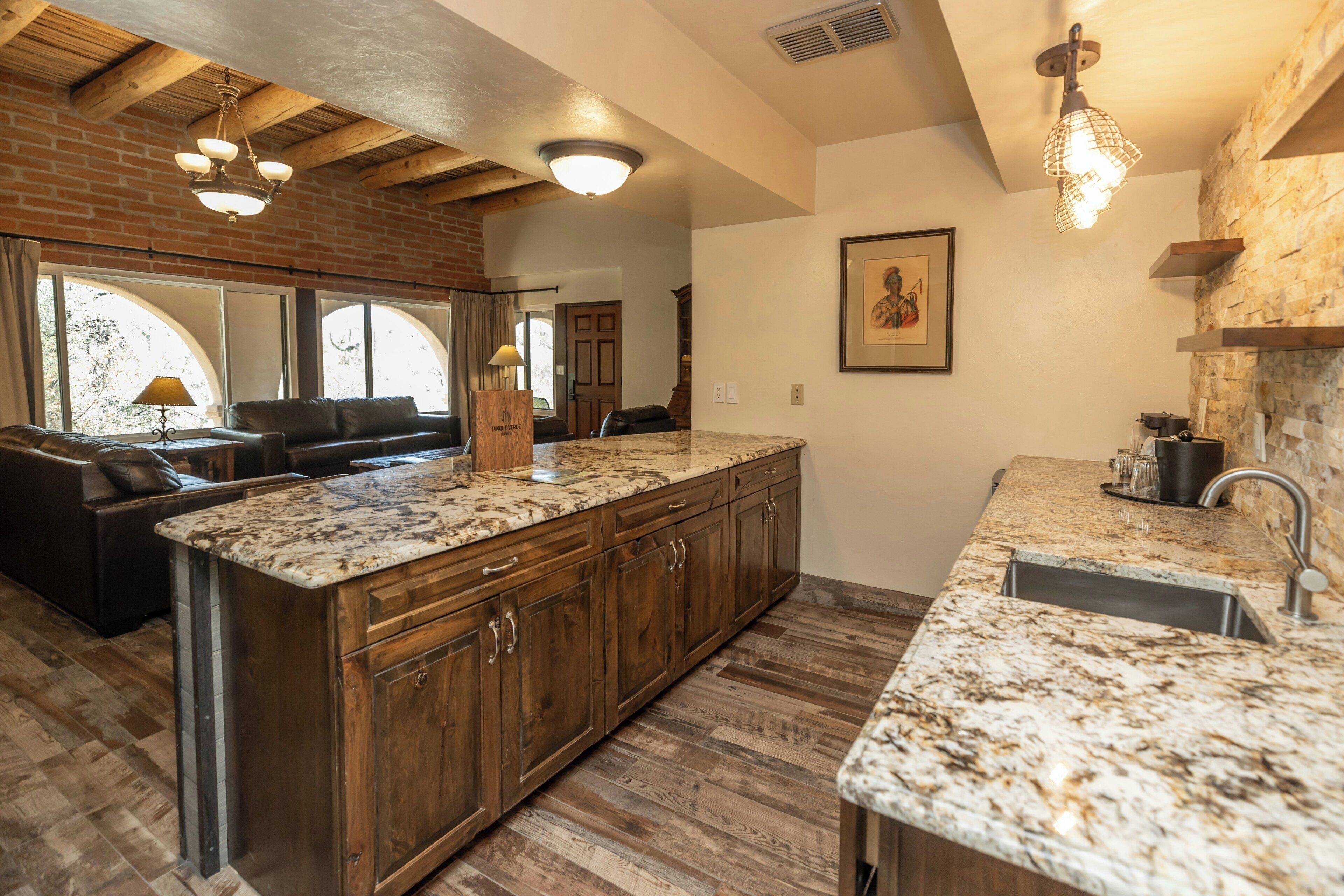 A kitchen with a large island, wooden cabinets, and a stone backsplash.