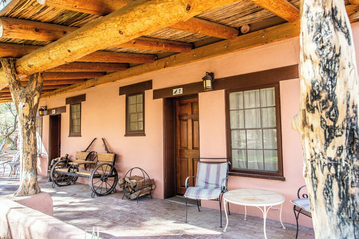 A covered porch with a wooden ceiling, a bench, a chair, and a table.