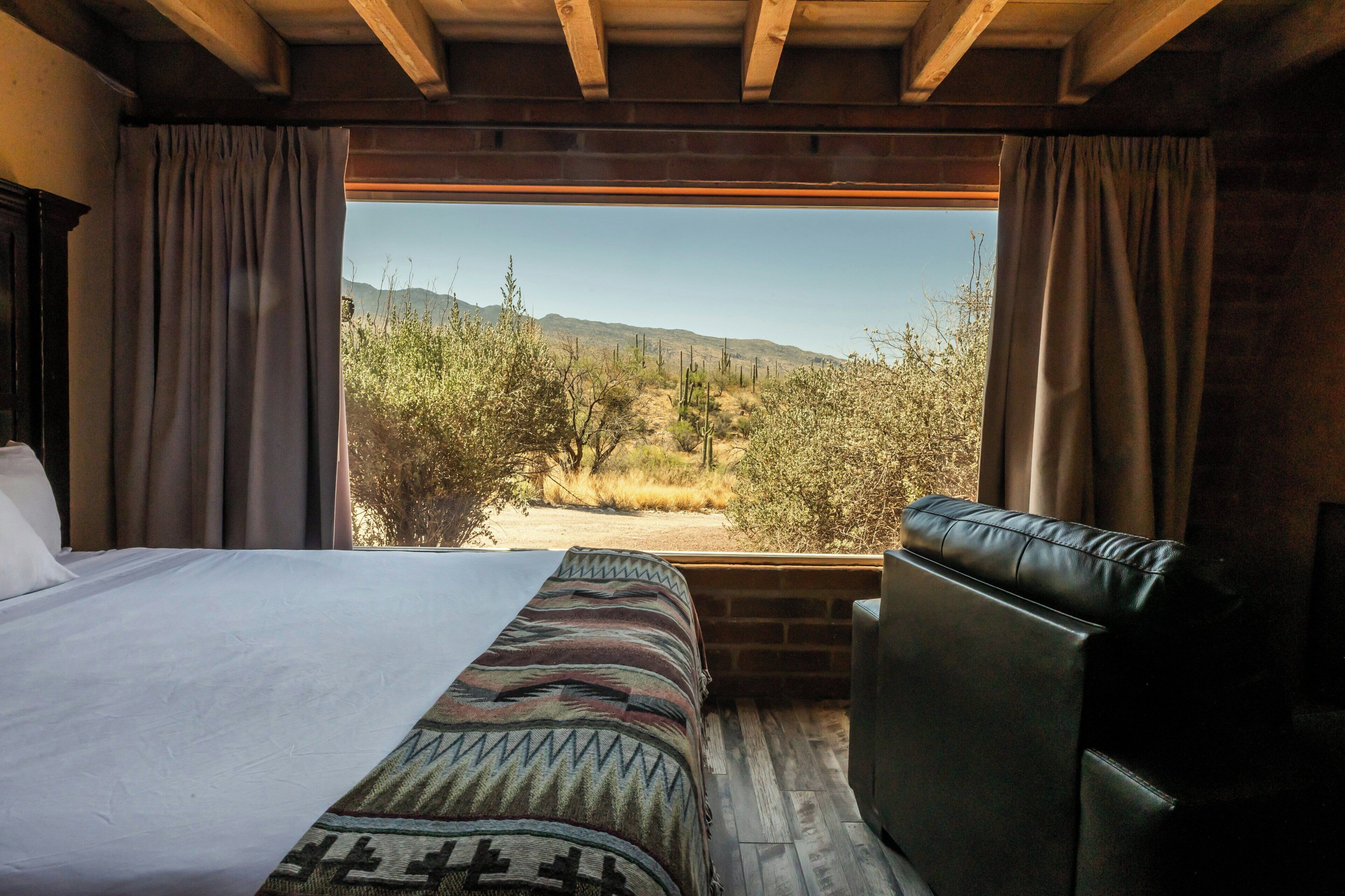 Une chambre avec un grand lit, un canapé et une vue sur un paysage désertique.