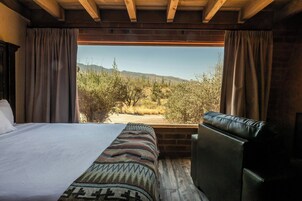 Un dormitorio con una cama grande, un sofá y vistas a un paisaje desértico.