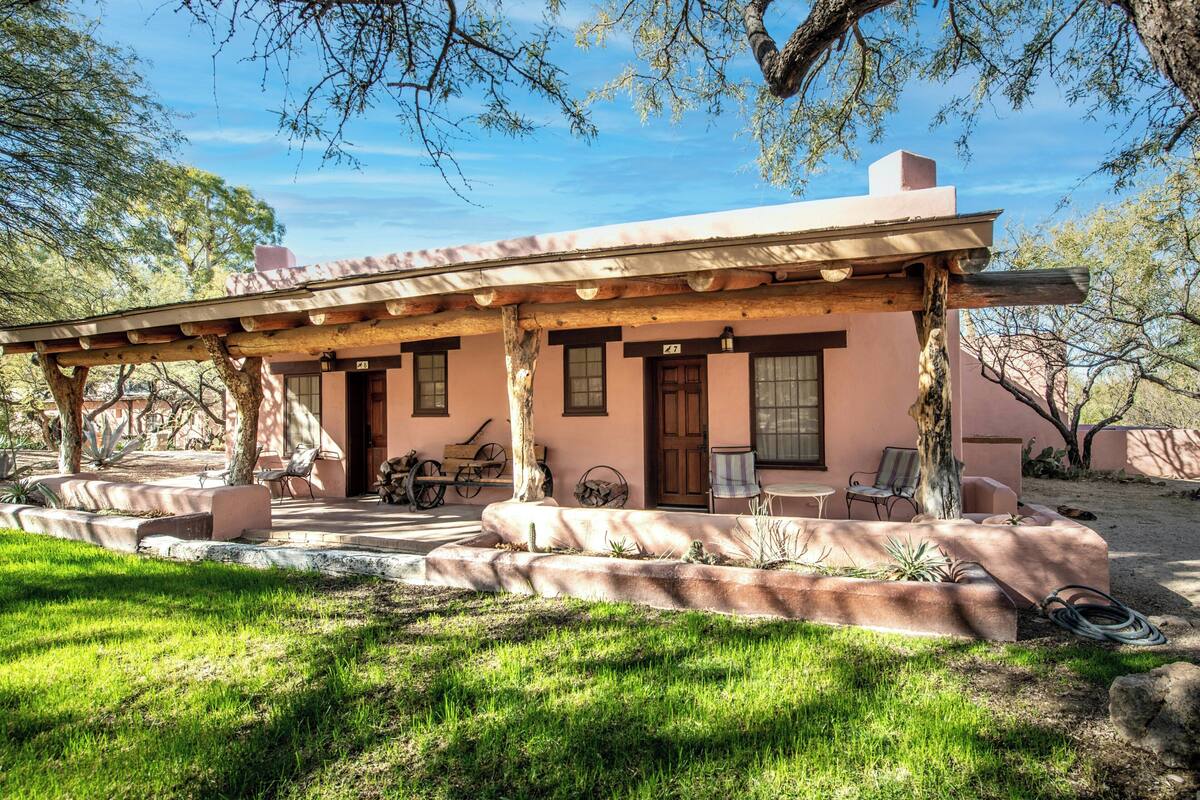 A house with a covered porch, a patio with seating, and a small garden area.