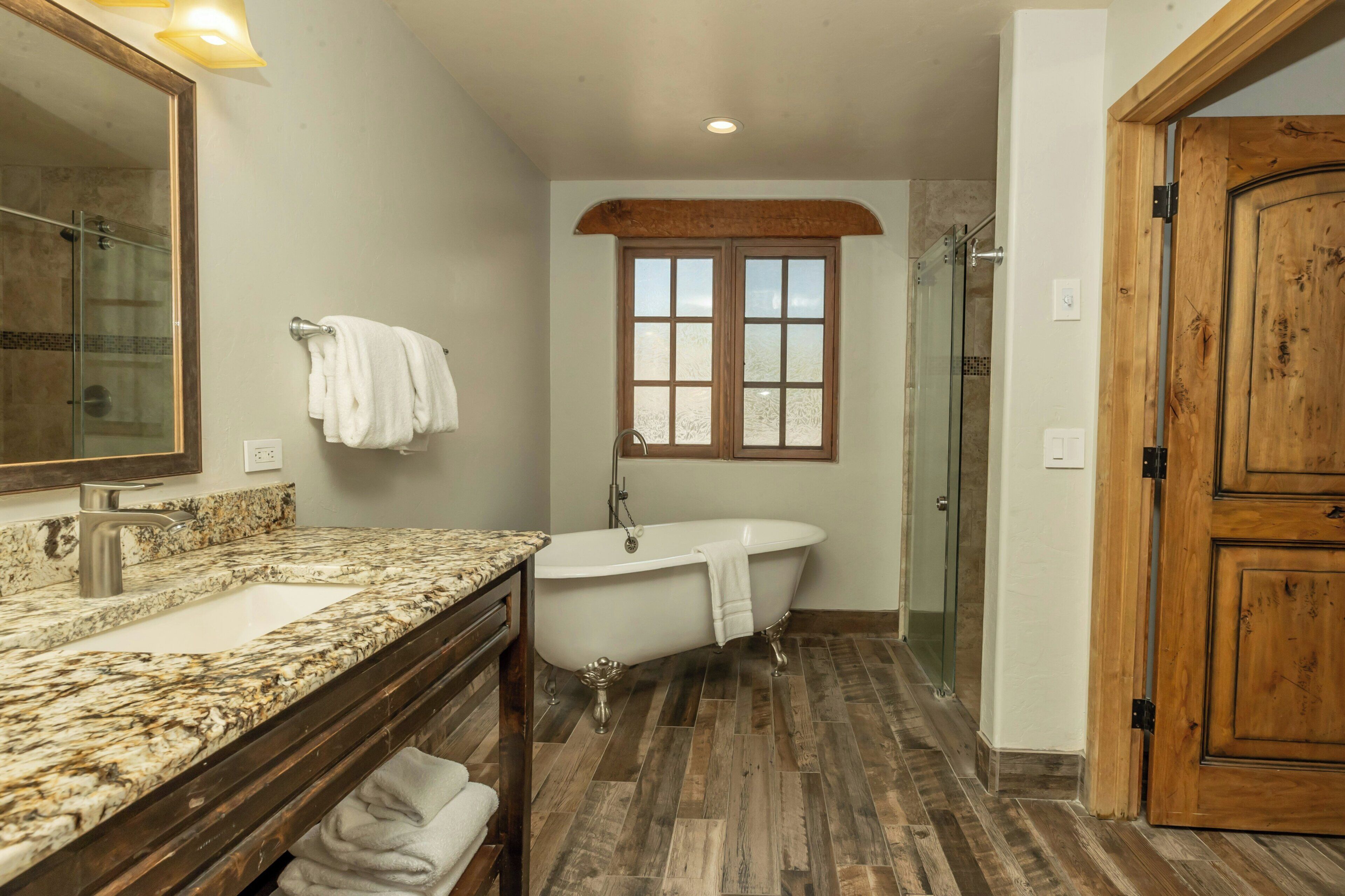 Un bagno con un lavabo in marmo, una vasca da bagno freestanding e una porta in legno.