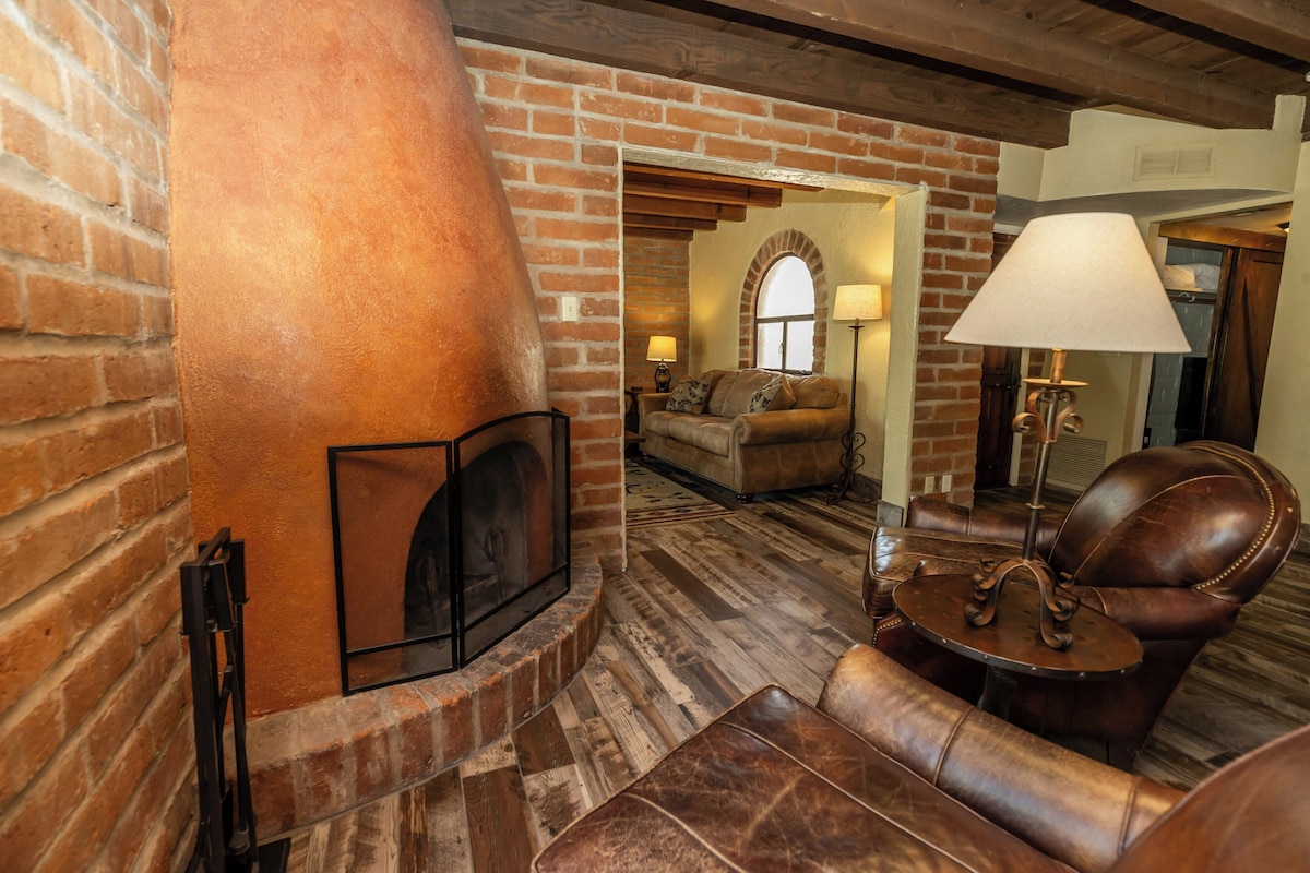Una habitación acogedora con chimenea, muebles de cuero y pared de ladrillo.