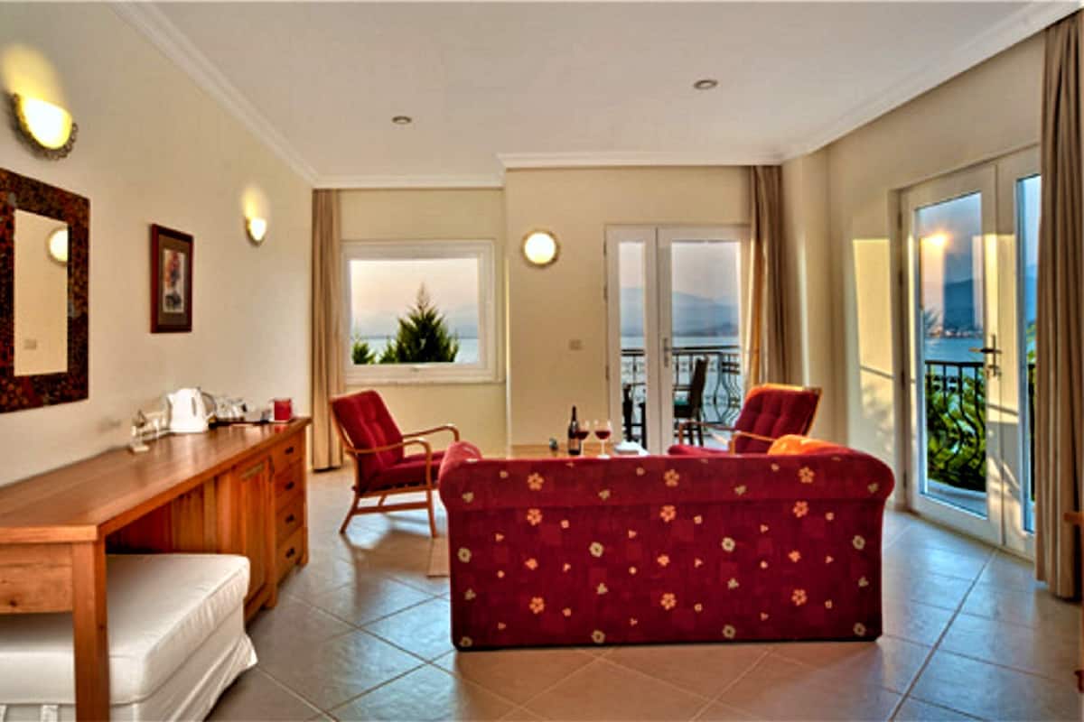 A living room with a wooden desk, a red sofa, and a balcony with a view.