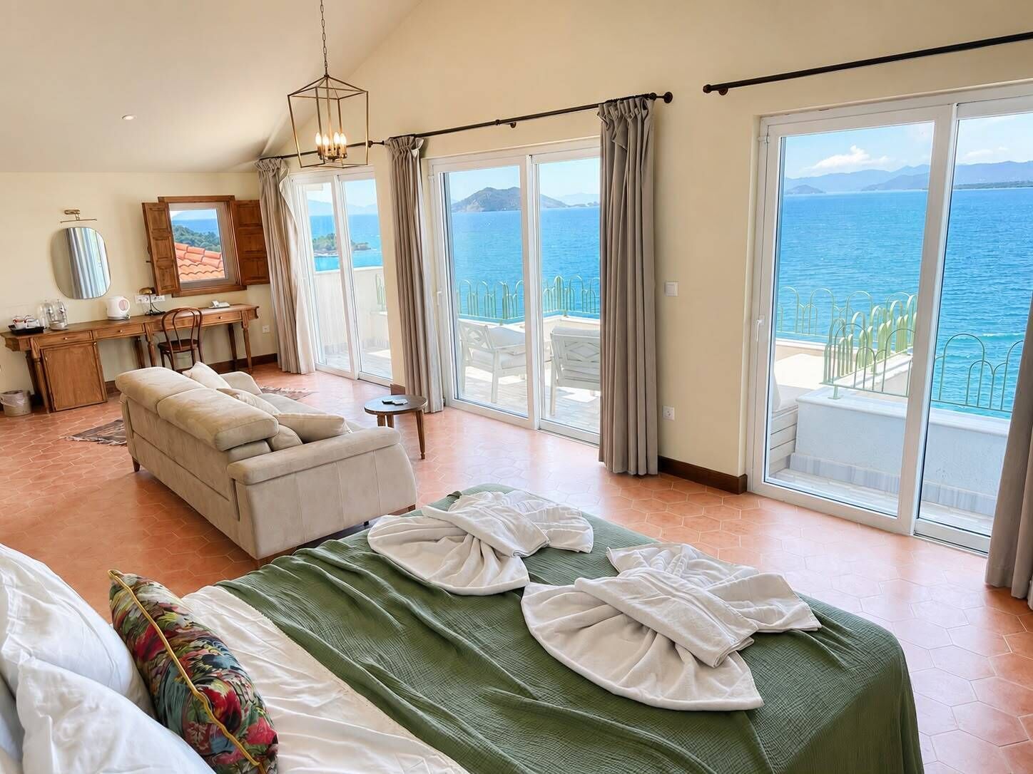 Ein Hotelzimmer mit Bett, einer Sitzecke, einem Schreibtisch und Blick auf das Meer.