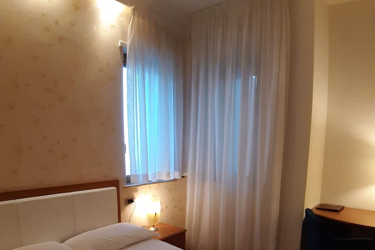 Une chambre d’hôtel avec un lit, un bureau et une table de chevet.