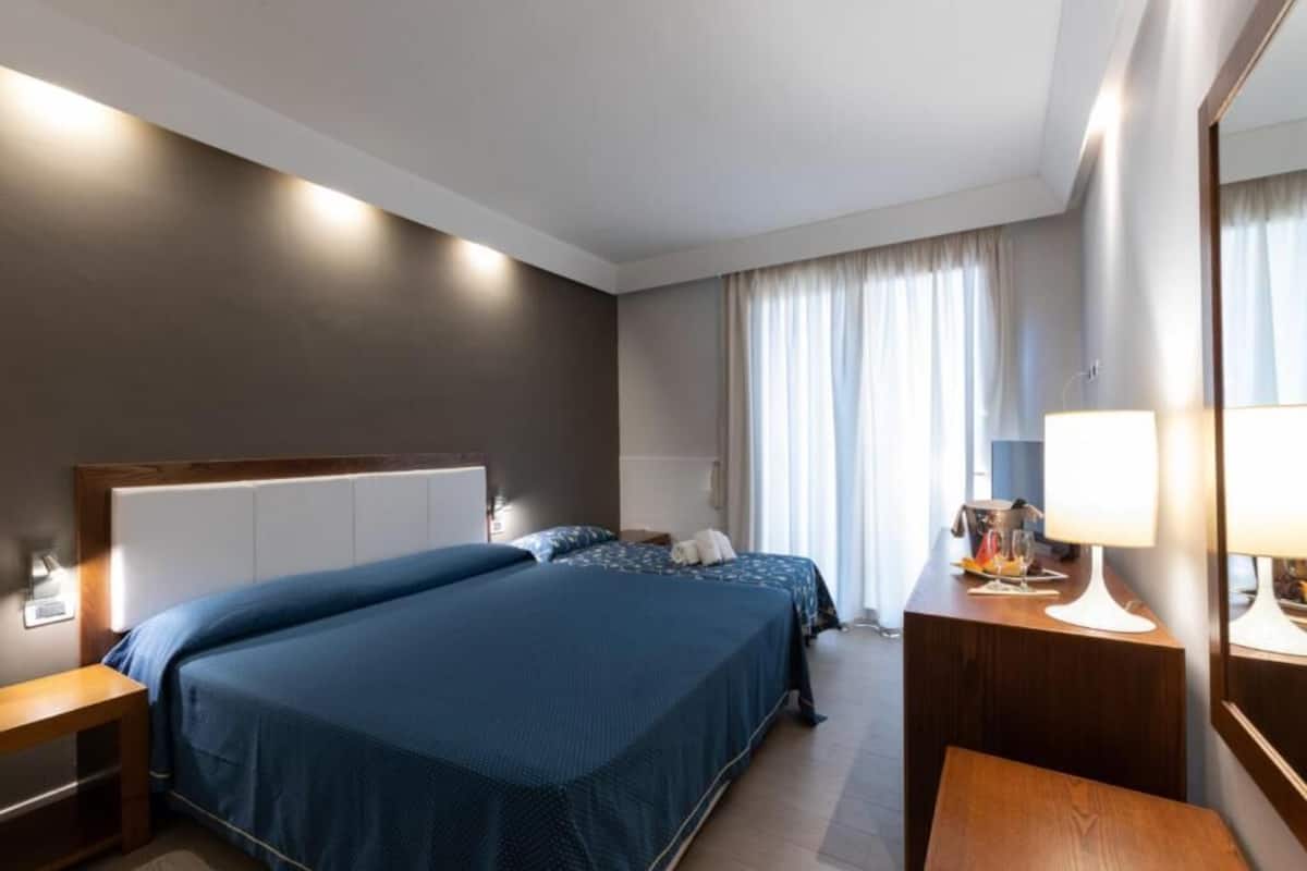 Une chambre d’hôtel avec un grand lit, une table de chevet, un bureau et un miroir.