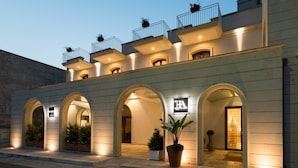 Un hotel con varios balcones, entradas arqueadas y plantas en macetas.
