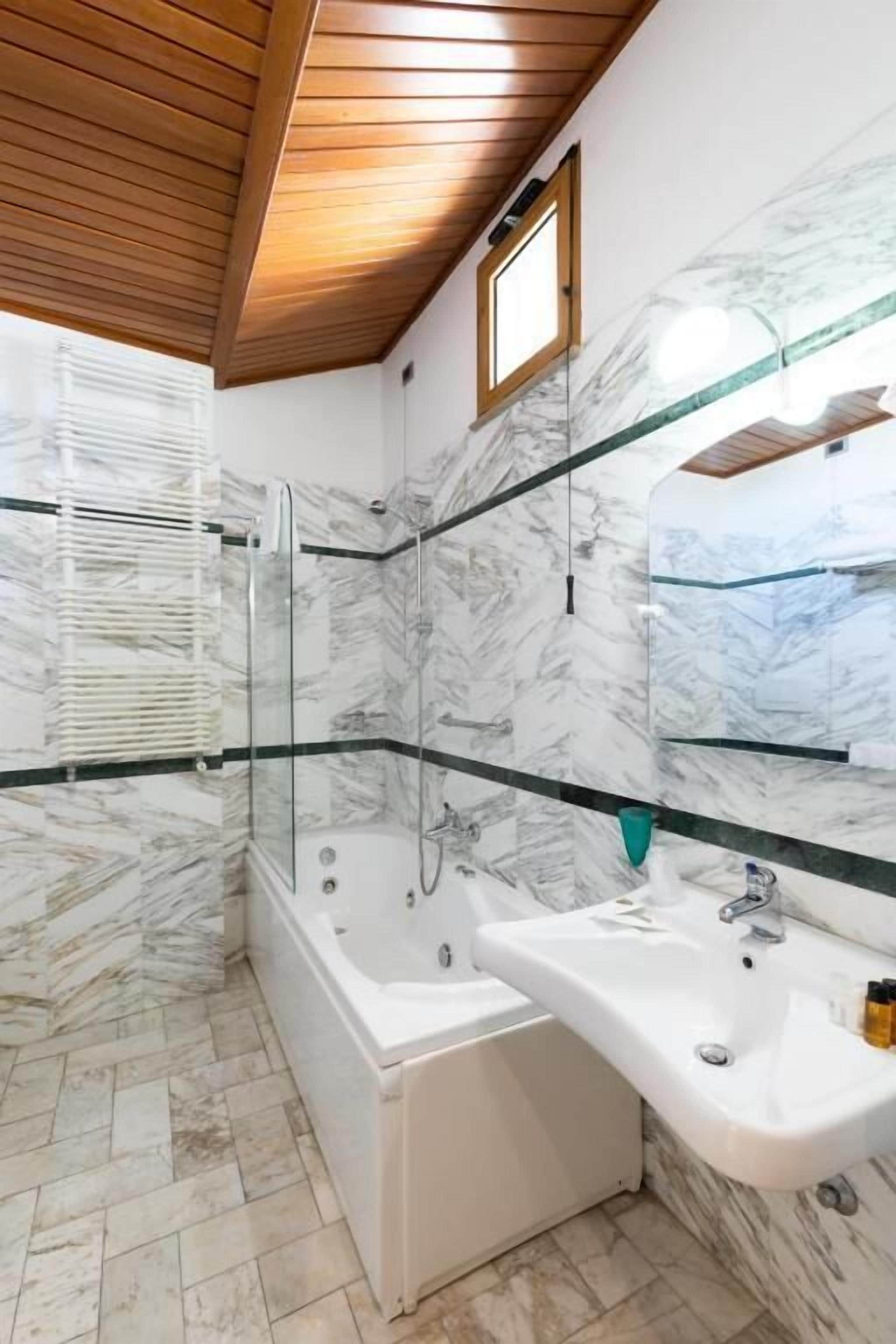 A modern bathroom with a glass-enclosed shower, a freestanding bathtub, and a vanity with a mirror.