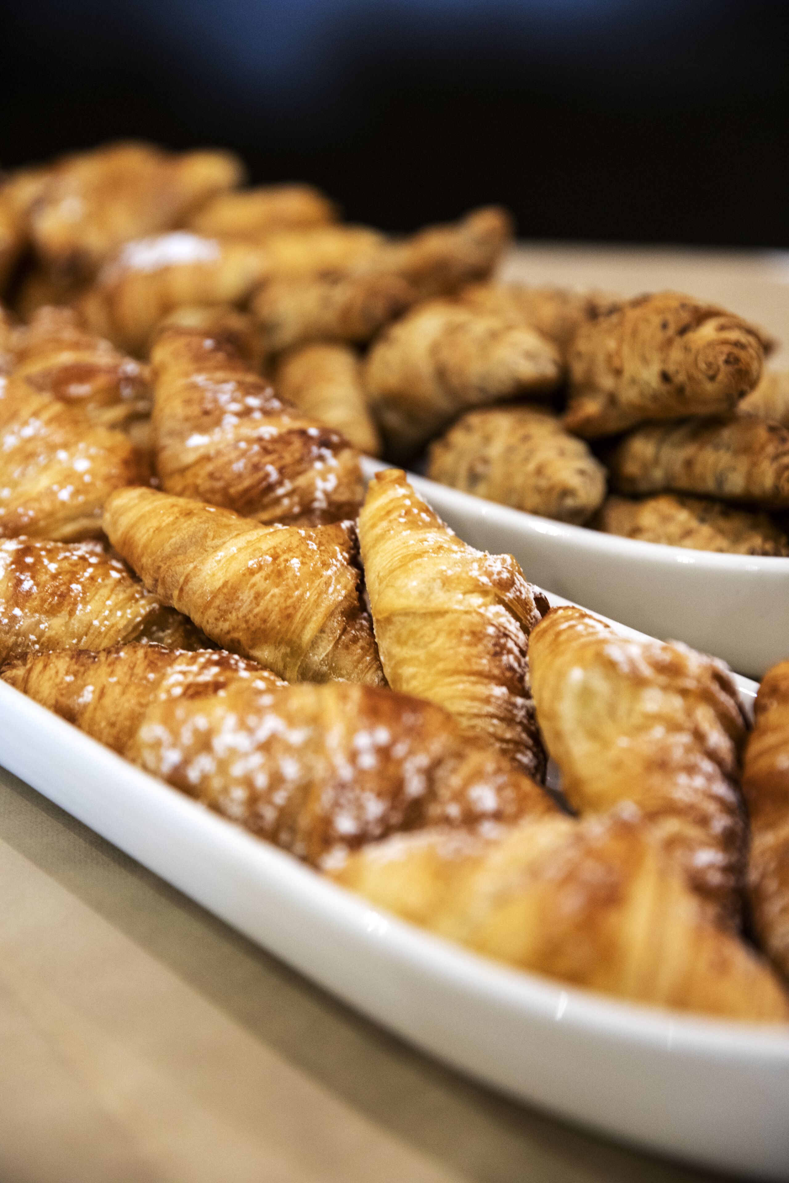 Verschiedene Backwaren, darunter Croissants und andere Gebäckstücke, auf einem weißen Teller angerichtet.