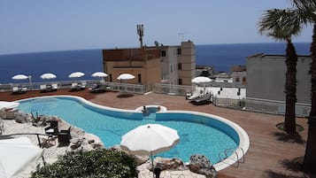 Una piscina al aire libre, sombrillas, sillones reclinables de piscina