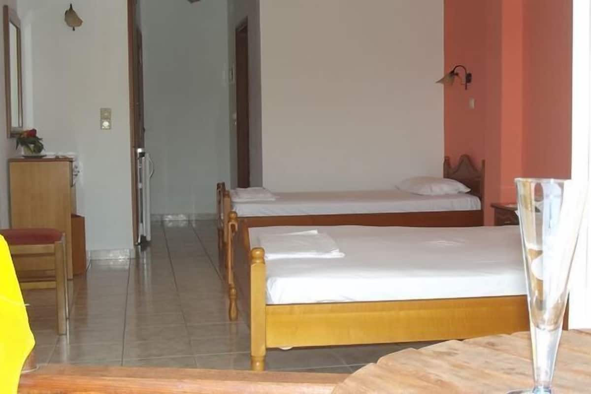 A hotel room with two beds, a wooden dresser, a chair, and a bottle of wine on the table.