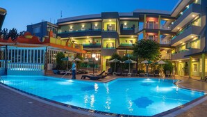 Een hotel met een zwembad, meerdere balkons en buitenzitplaatsen.