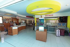 Un espace d’accueil avec un comptoir, un panneau indiquant « DÉPÔT DE BAGAGES » et un présentoir de valises.