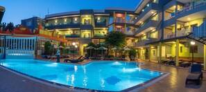 Un hotel con piscina, varios balcones y zonas de estar al aire libre.