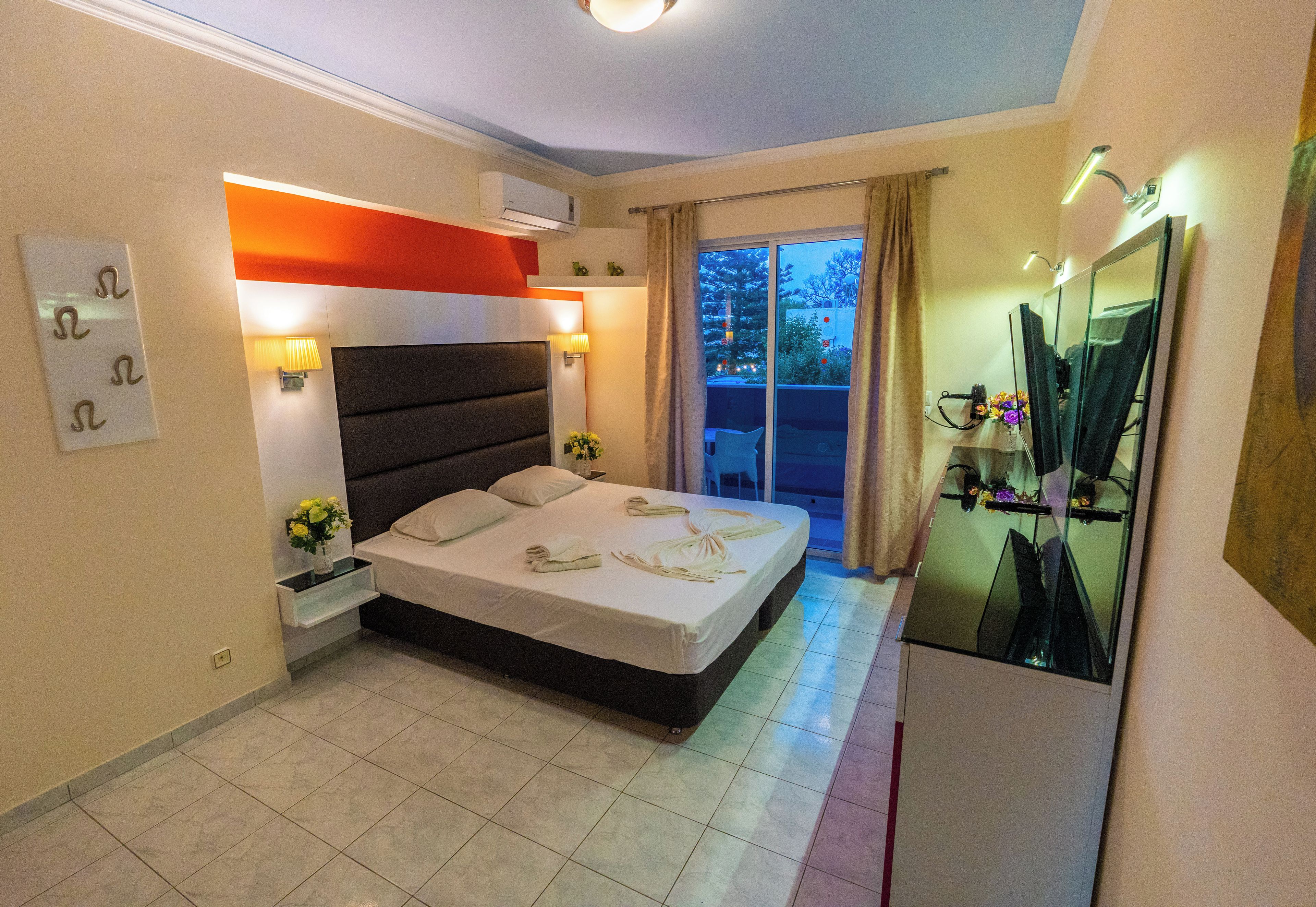Un dormitorio moderno con cama, lámparas de noche, mesita de noche, espejo y vistas al exterior.