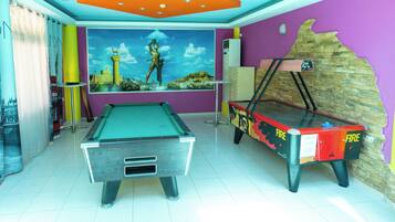 Una sala con mesa de billar, mesa de snooker y un mural de una escena histórica.