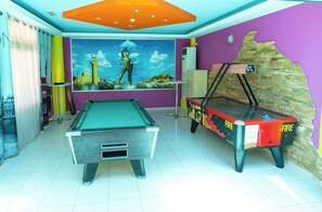 A room with a pool table, a snooker table, and a mural of a historical scene.