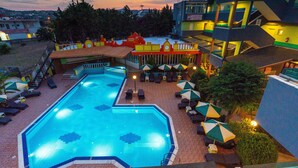 Une piscine entourée de bâtiments dotés de balcons, avec des chaises longues et des parasols à proximité.