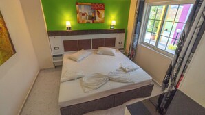 Hotelkamer met een bed, kussens, een groene accentmuur en een raam met gordijnen.