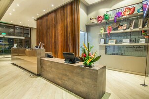 Un mostrador de recepción moderno con un panel de madera, una computadora portátil y una planta decorativa.