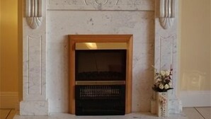 A fireplace with a marble surround, a wooden mantel, and a mirror above it. - Gort na Coiribe Holiday Village (Galway)