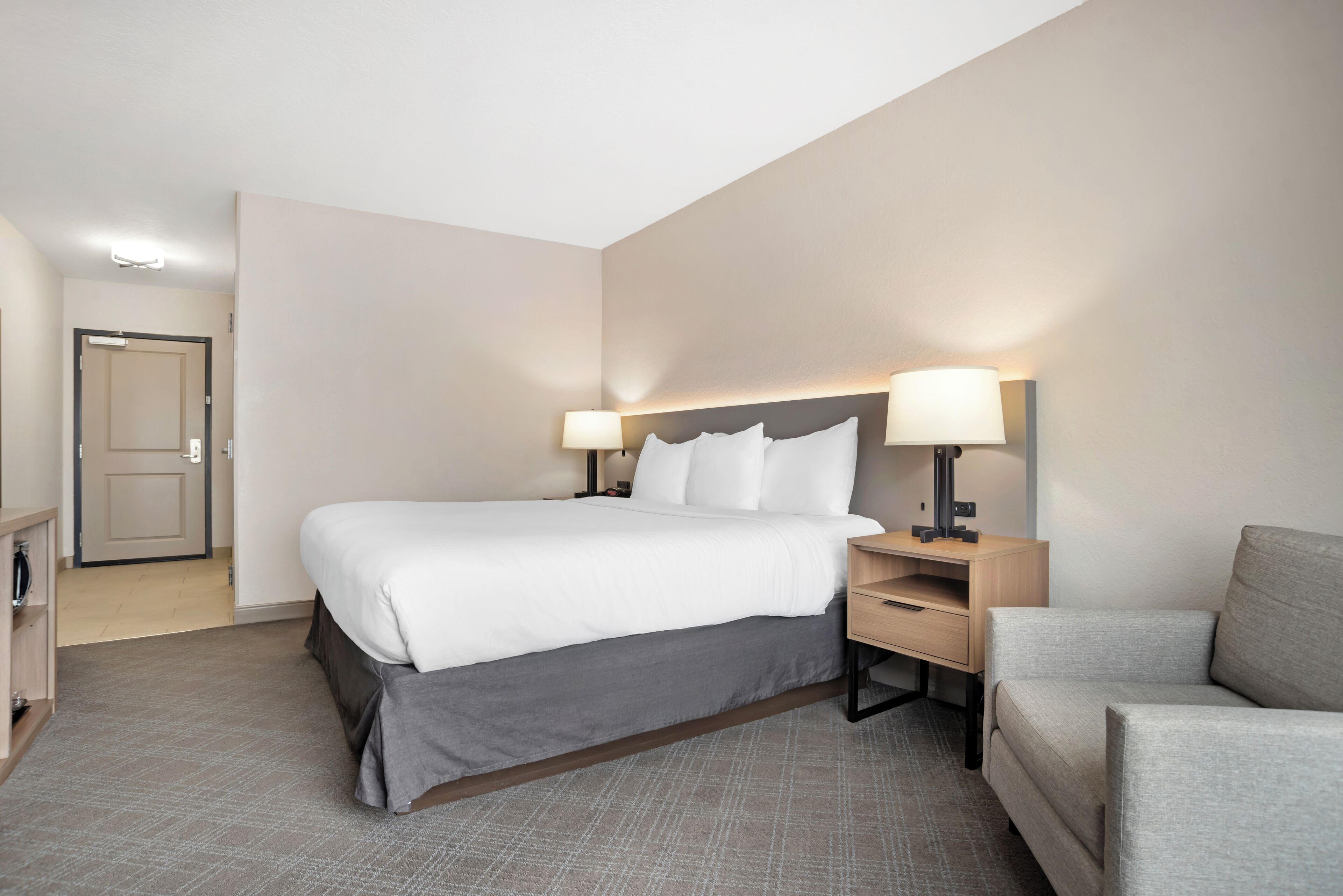 A hotel room with a bed, bedside tables, a desk, and a chair.