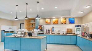 A modern kitchen with blue cabinets, a central island, and various appliances. - Comfort Inn & Suites Slidell - New Orleans Area (Slidell)