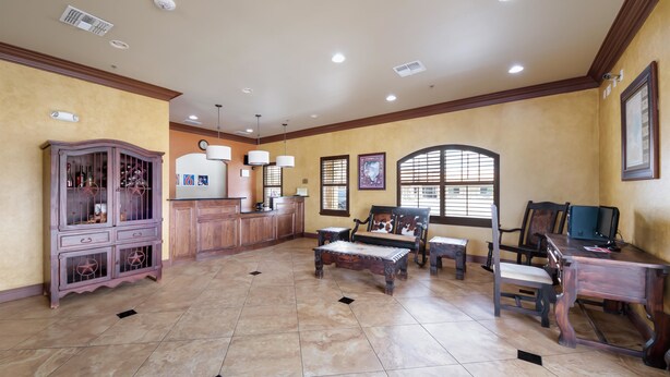 A spacious living room with a wooden cabinet, a sofa, a coffee table, and a desk. - Eagle Ford Inn (Floresville)