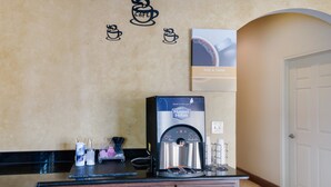 A coffee station with a Maxwell House coffee maker, a coffee cup, and a coffee mug on the counter. - Eagle Ford Inn (Floresville)