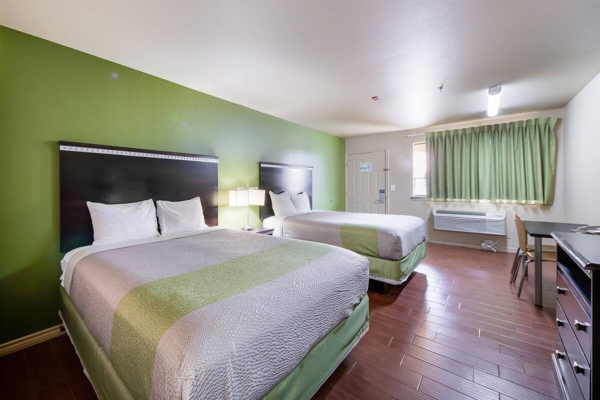 A hotel room with two beds, a desk, and a chair.