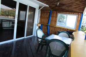 An outdoor patio area with a table and chairs, a sliding glass door, and a view of a body of water. - Subiza Beach Resort (Olongapo)