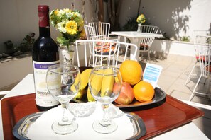 Una bandeja con una botella de vino Maykop, dos copas de vino y un plato de fruta que incluye plátanos, manzanas y naranjas.