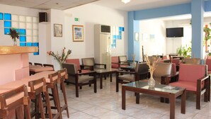 Un hall d’hôtel comprenant un comptoir d’accueil, un espace salon et un téléviseur fixé au mur.
